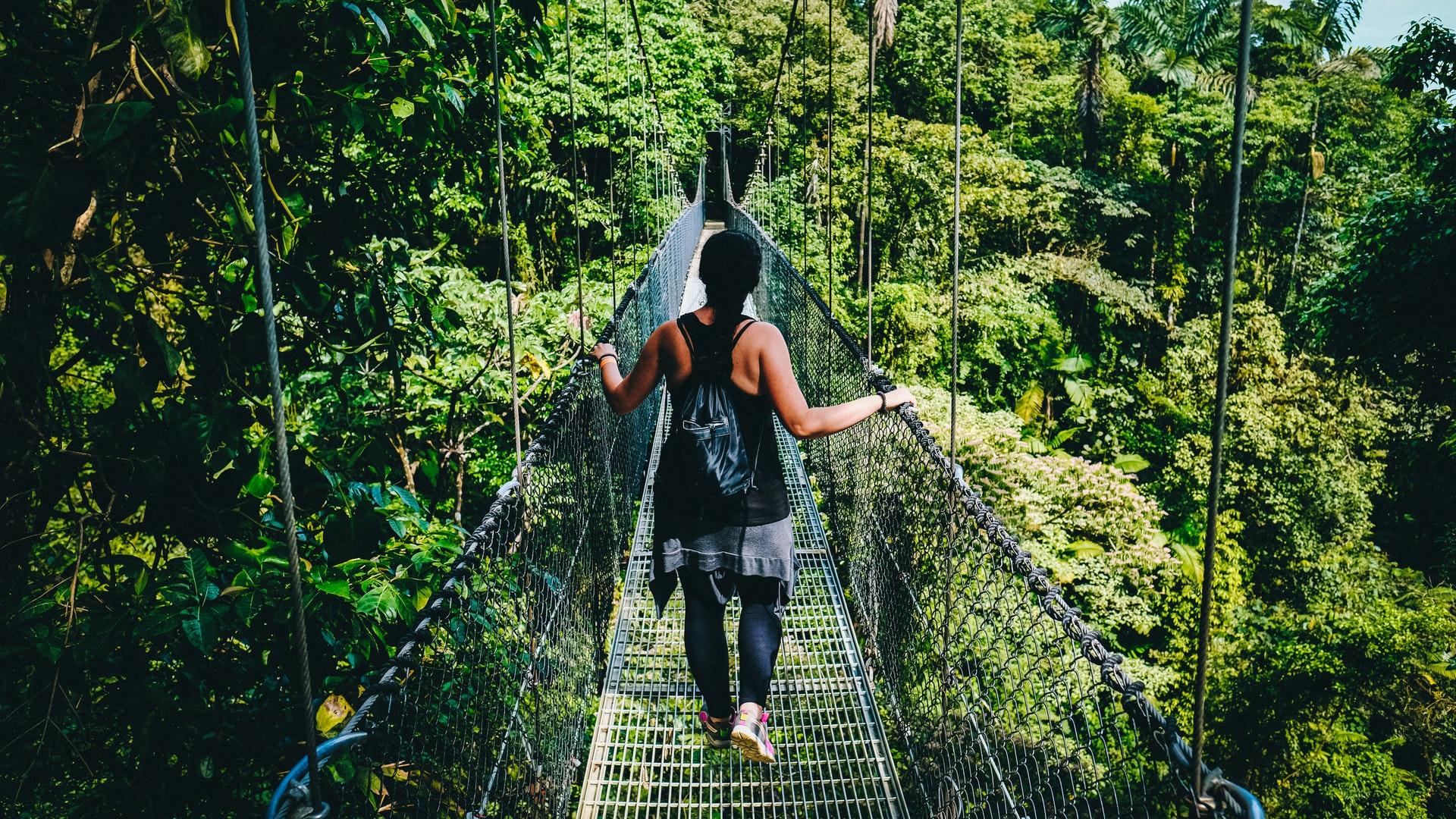 woman in black shirt and black pants standing on hanging bridge